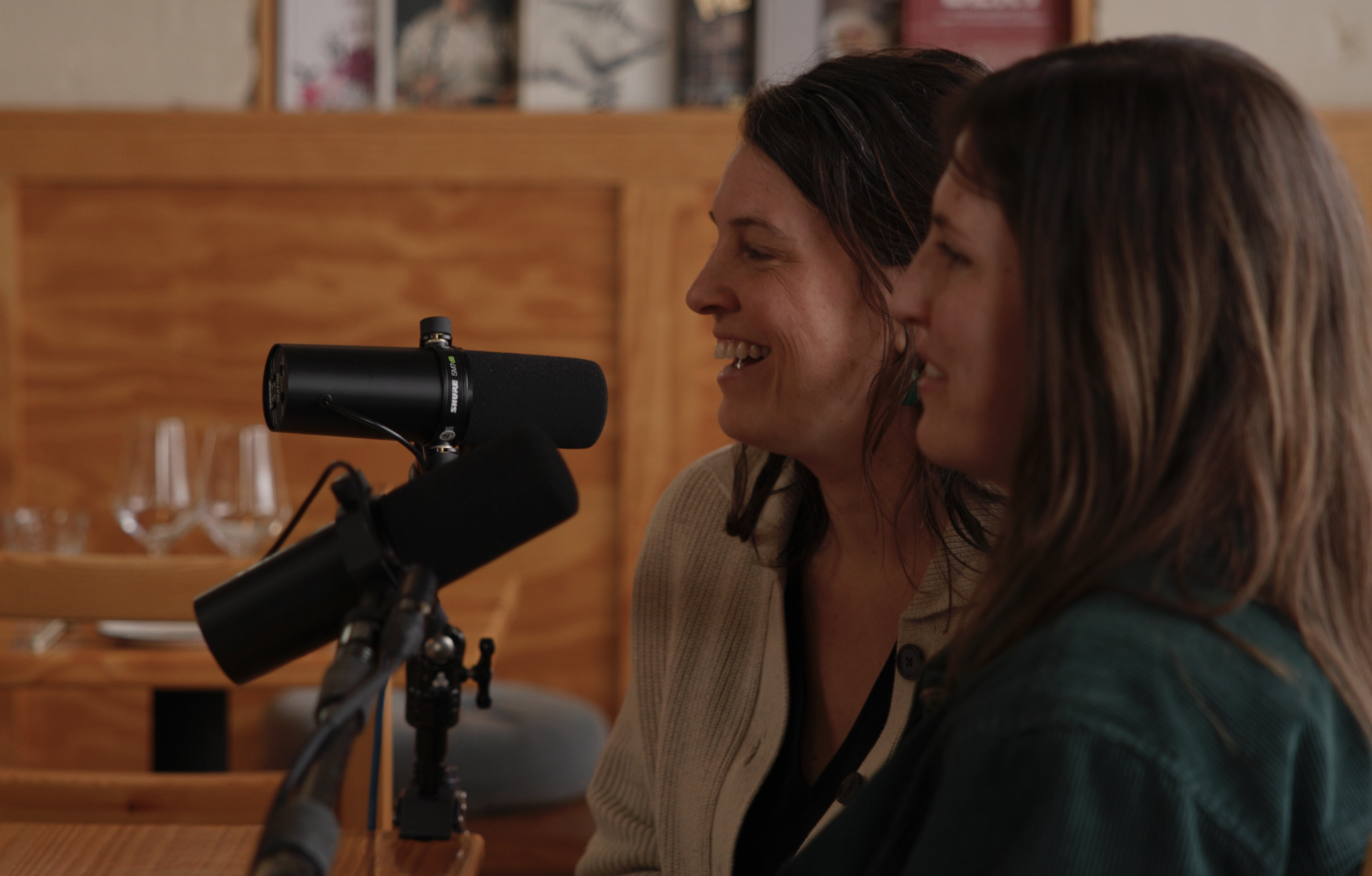 Tricia Phelps and Emily Row speaking into microphones at a table