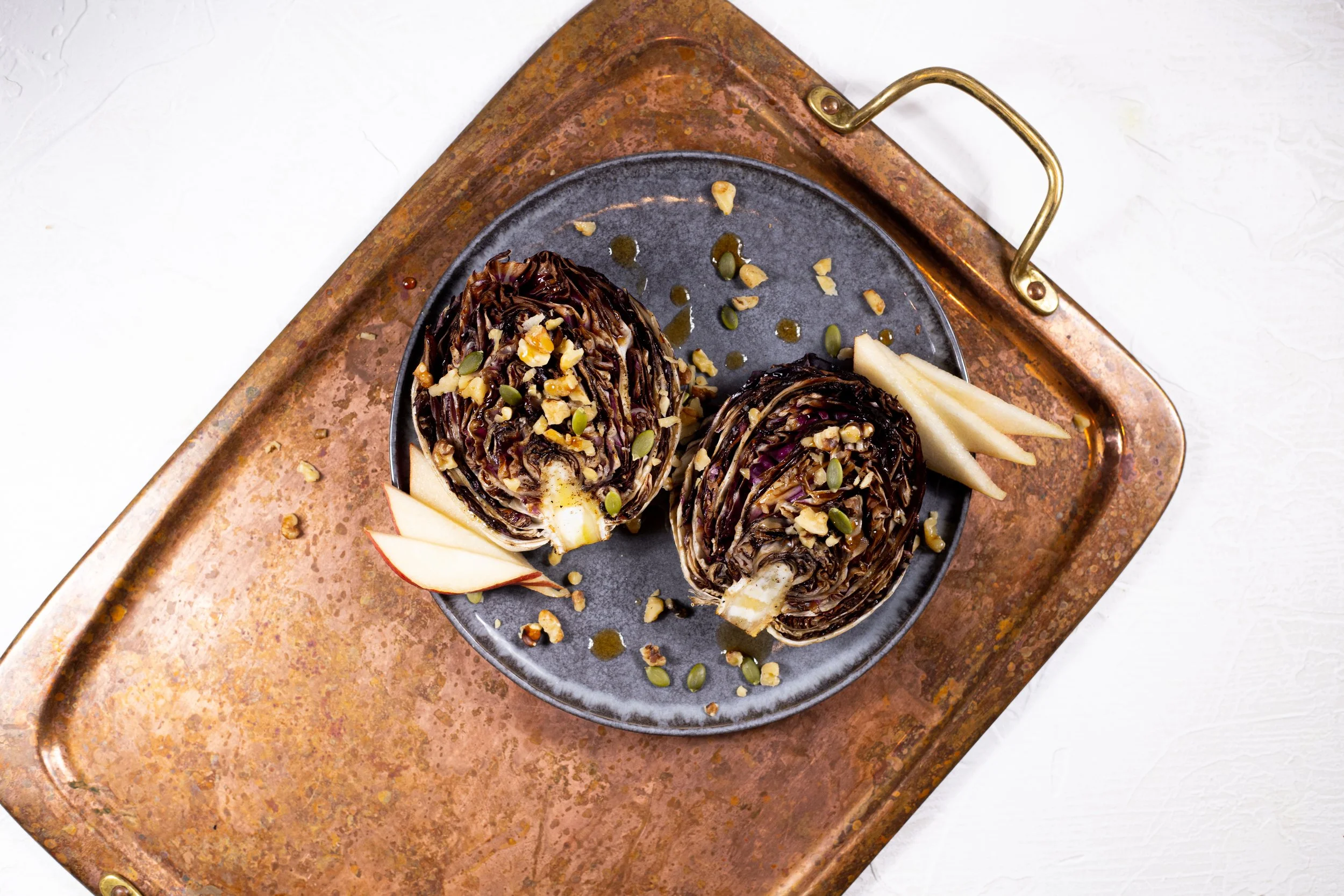 A serving tray with roasted radicchio topped with pepitas and sliced apples