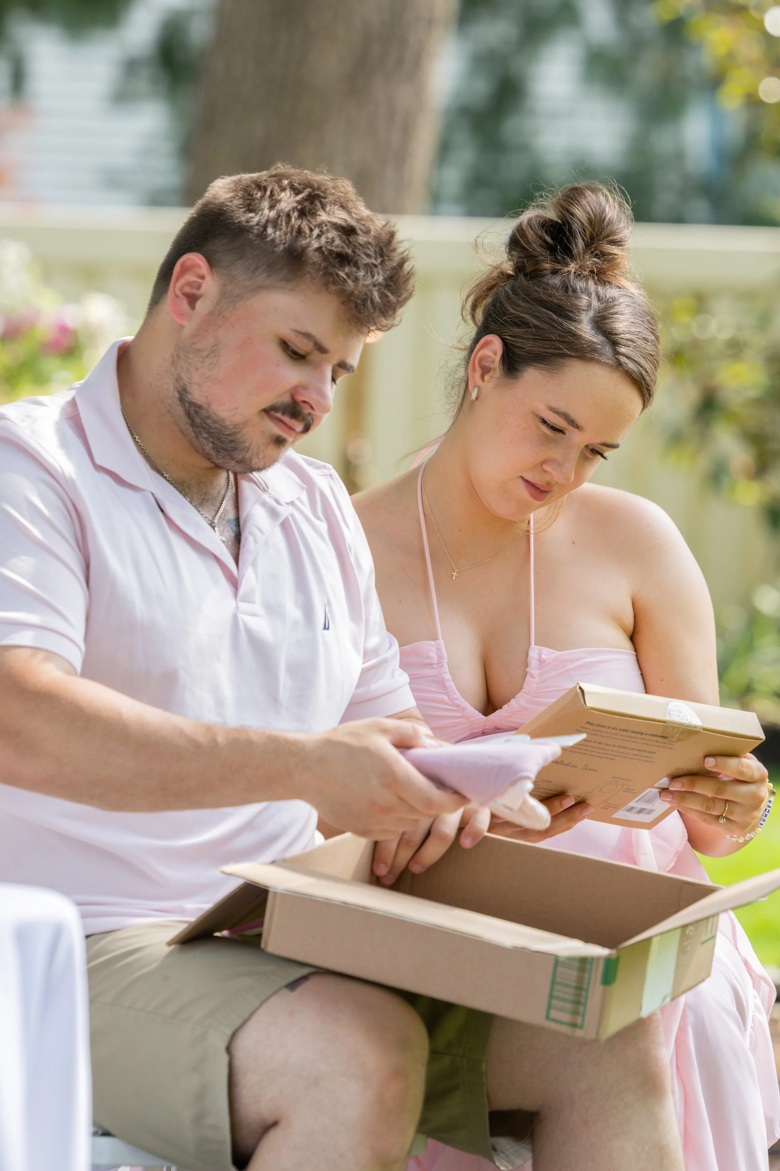 Young couple opening gifts at a baby shower on a sunny summer day