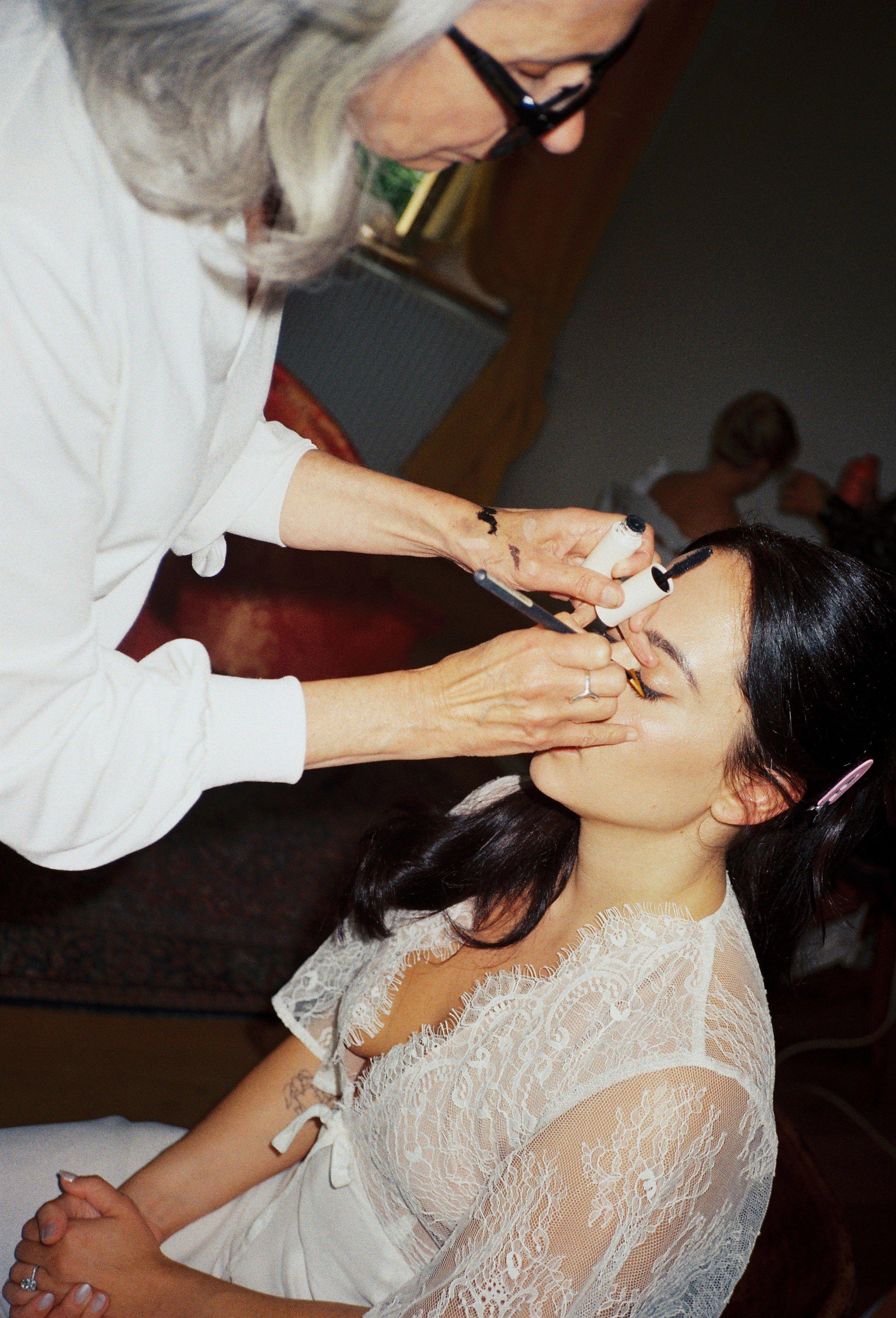 Film photography wedding morning getting-ready moment at Château Gassies near Bordeaux, France by Cleya Asulon, destination wedding photographer for Bordeaux and the Gironde region — bride seated with eyes closed and a soft smile, wearing a delicate 