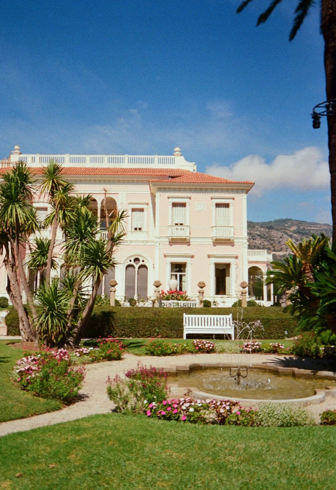 Film photography frame of Villa Ephrussi de Rothschild on the French Riviera by Cleya Asulon, destination wedding photographer for the Côte d'Azur — Belle Époque pink Italianate villa with terracotta roof tiles and arched windows seen across manicure
