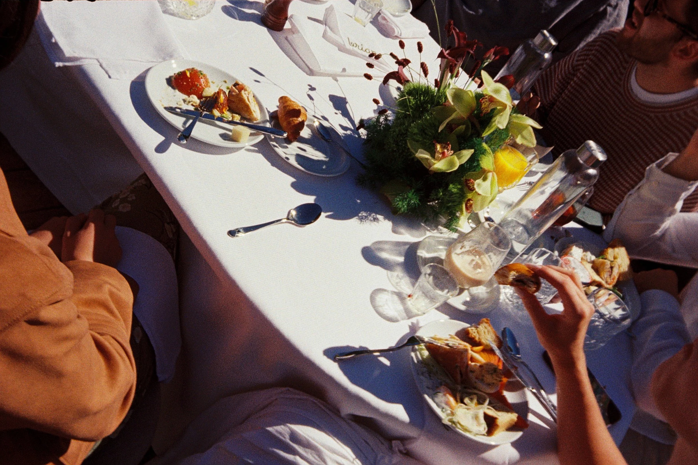 Film photography editorial wedding brunch detail at a private chalet in the French Alps near Megève by Cleya Asulon, destination wedding photographer for Megève, Mont-Blanc and the Haute-Savoie region — overhead view of a sunlit reception table dress