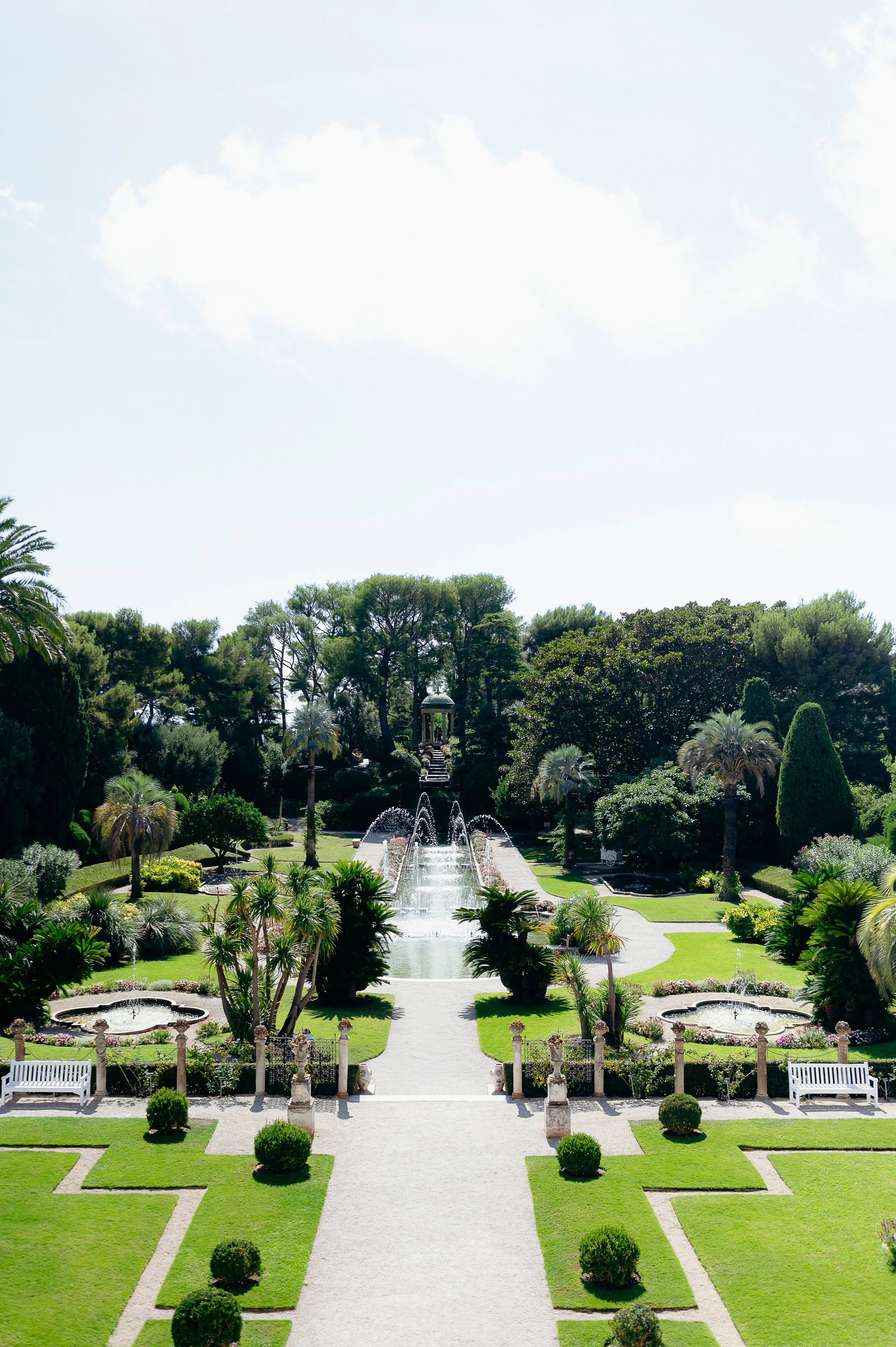 Luxury destination wedding venue on the French Riviera: the formal French garden of Villa Ephrussi de Rothschild in Saint-Jean-Cap-Ferrat, featuring a tiered central fountain, symmetrical parterres of clipped boxwood, palm trees, and the Temple of Lo