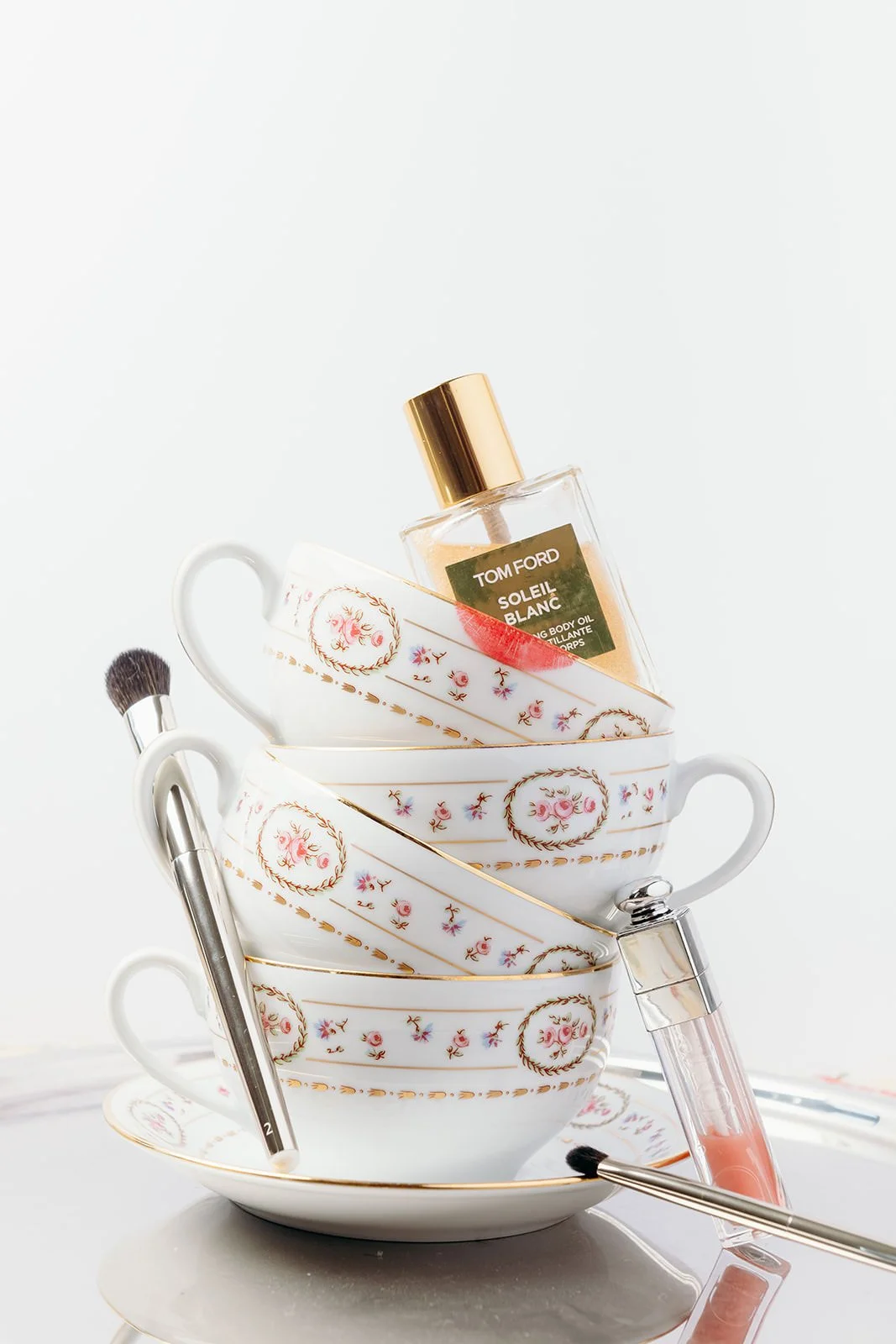 Editorial wedding morning still life at Château de Mirambeau (Gironde, France) by Cleya Asulon, destination wedding photographer based in Bordeaux and Cognac — playful stacked composition of three vintage porcelain teacups with rose-painted gold trim