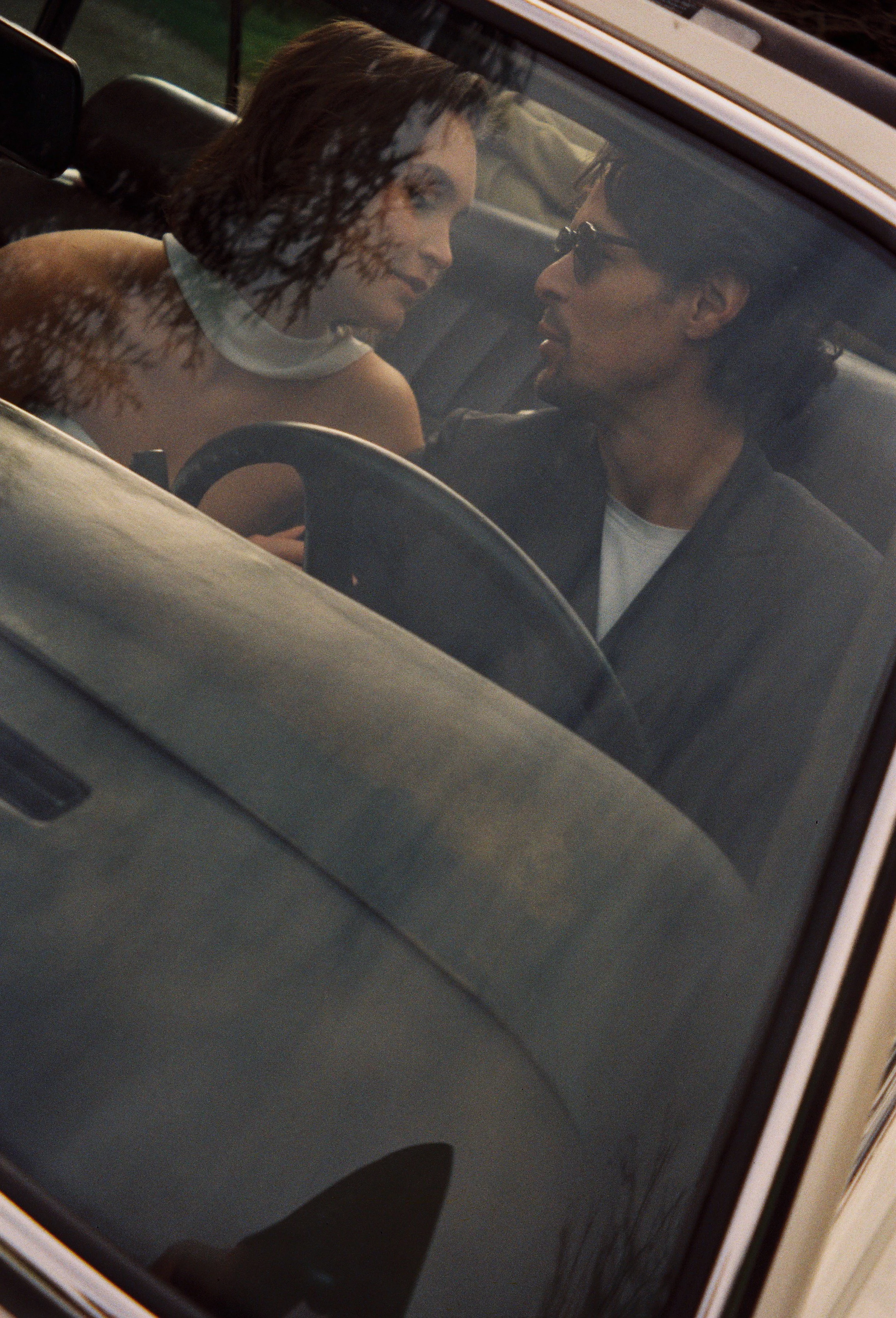 Film photography editorial couple portrait at Château de Bouffémont near Paris by Cleya Asulon, destination wedding photographer for Île-de-France and the Paris region — couple photographed through the window of a vintage car, the man in the driver's