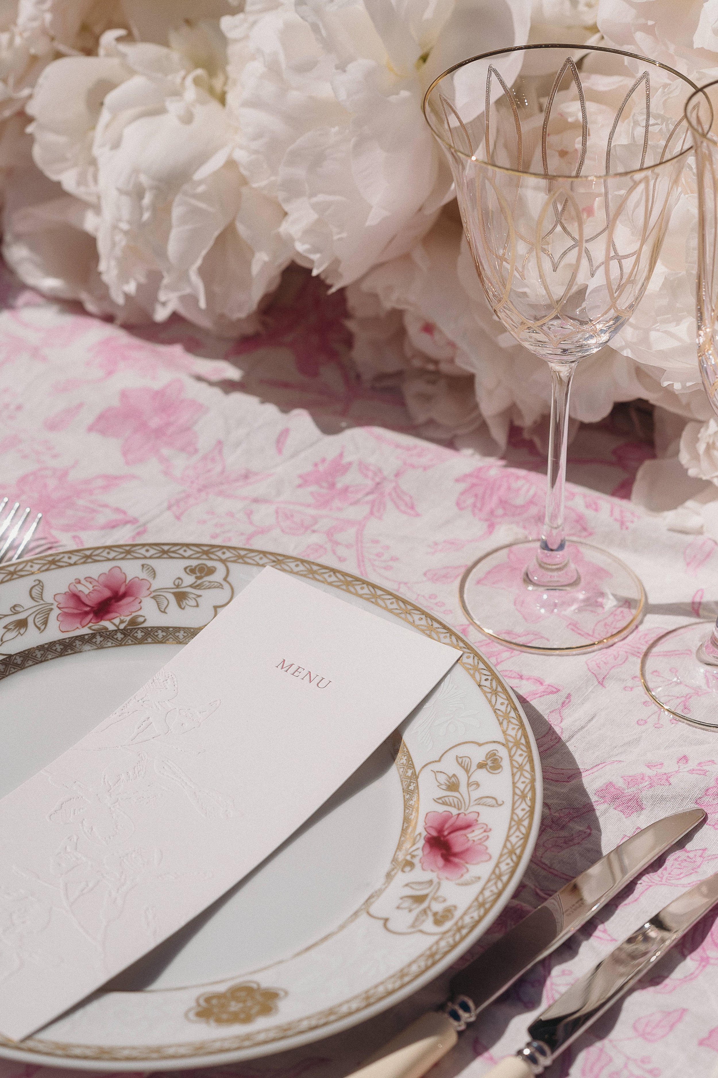 Destination wedding table detail photographed in France, featuring refined stationery, glassware and soft pink tones.
