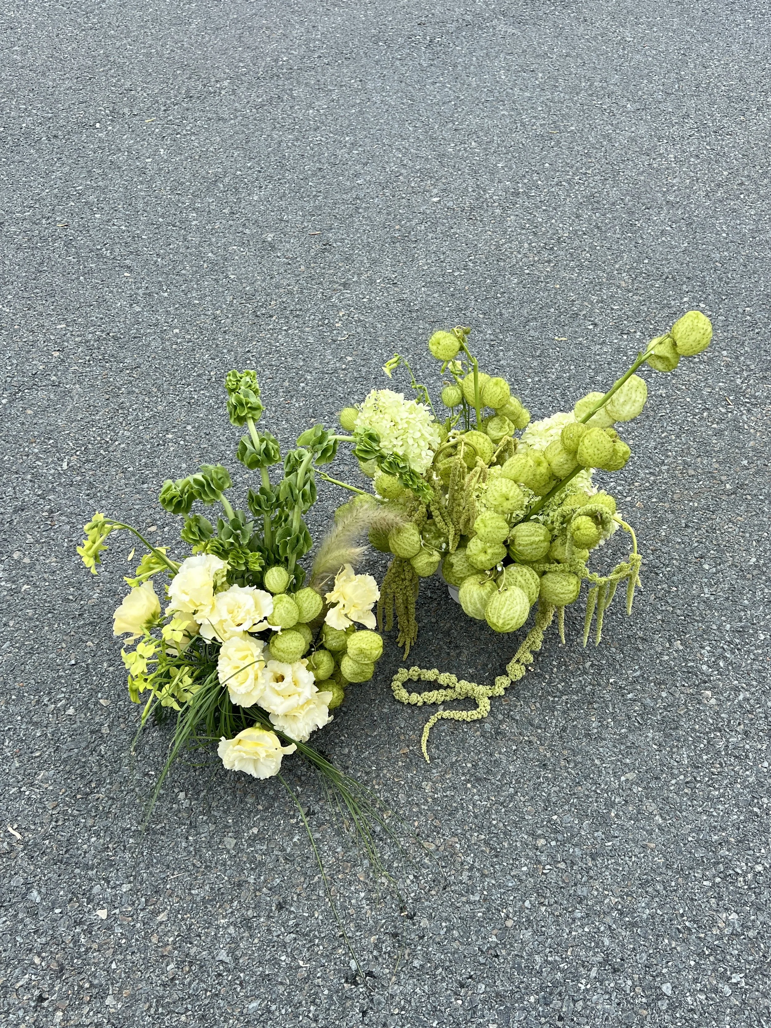 A floral arrangement with green and white flowers on asphalt ground.