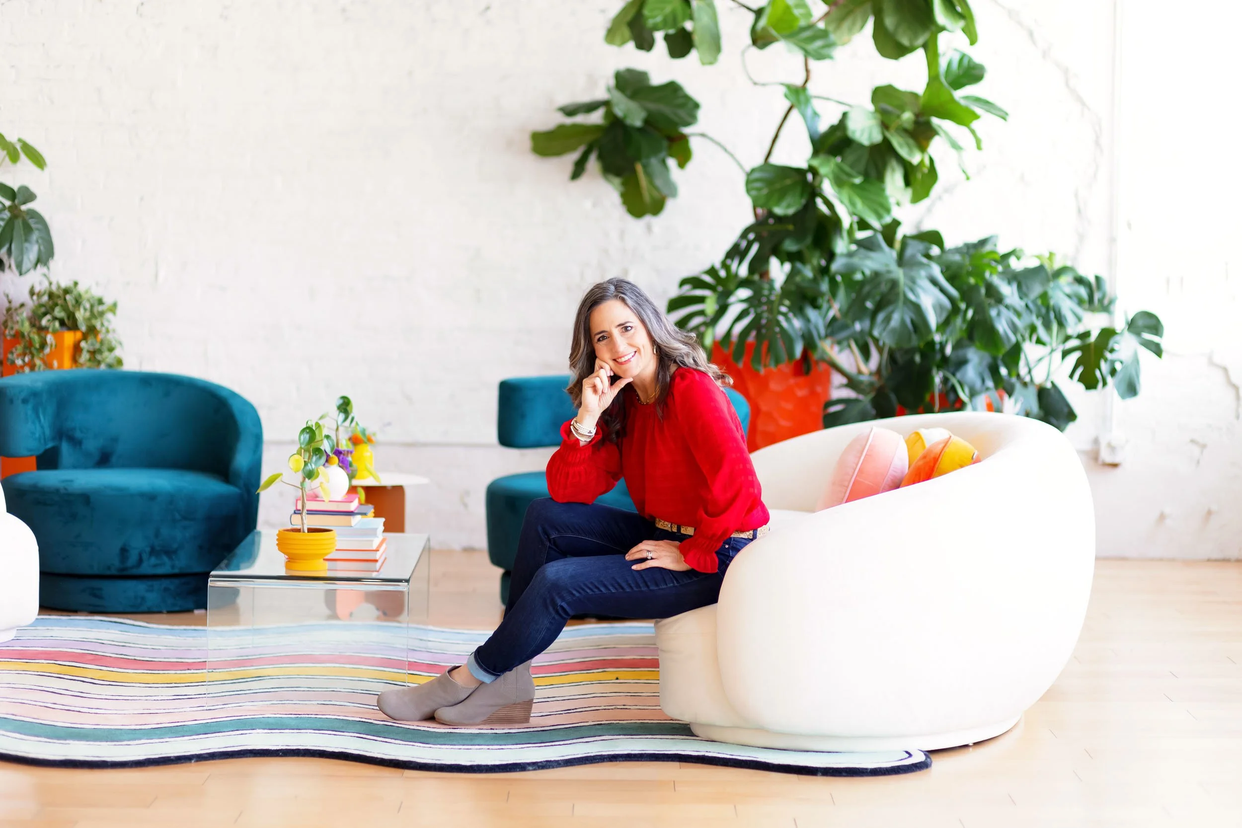 branding photo of a woman in a red blouse smiling on a white couch