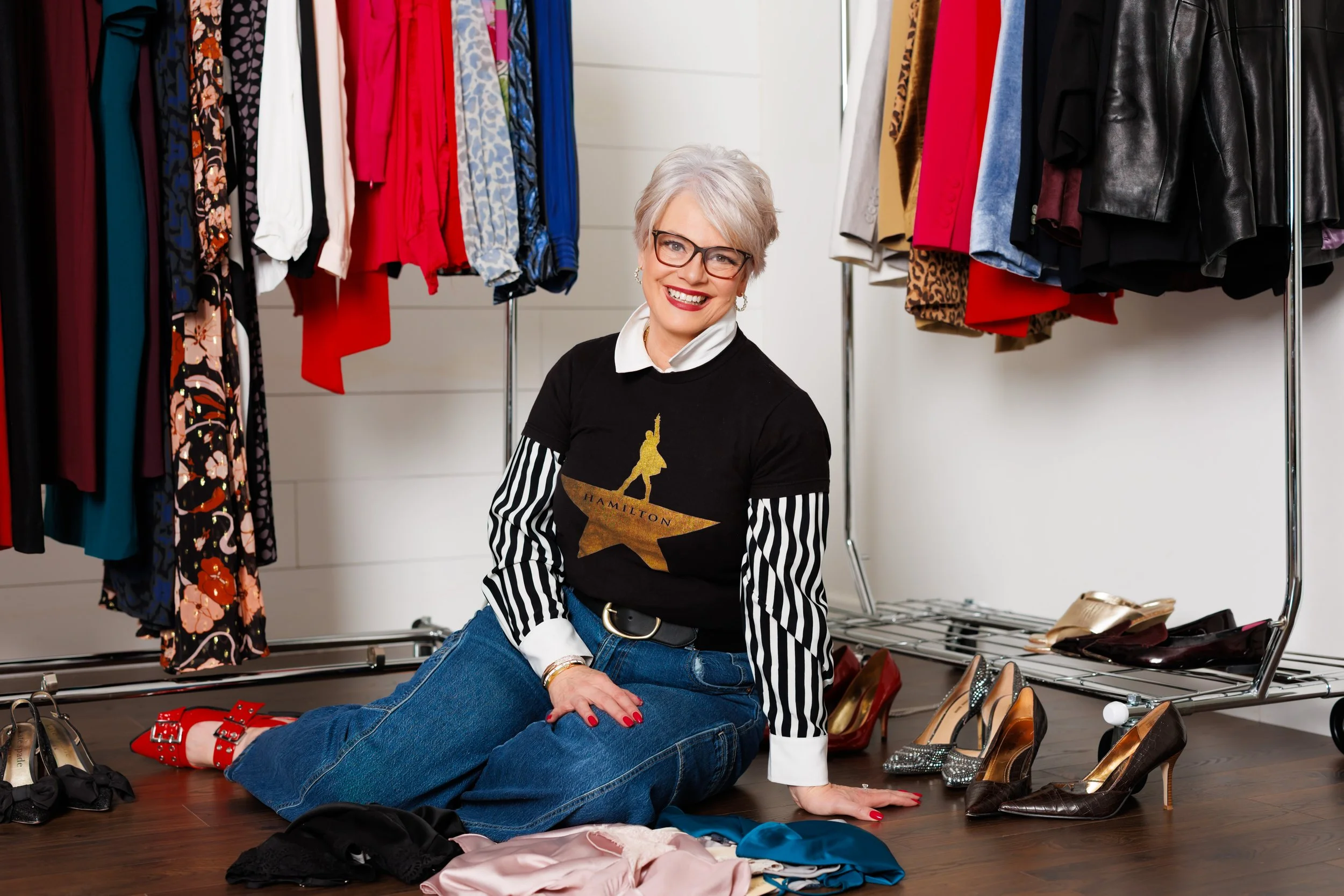 branding photo of a woman with gray hair in a closet with clothes and shoes surrounding her