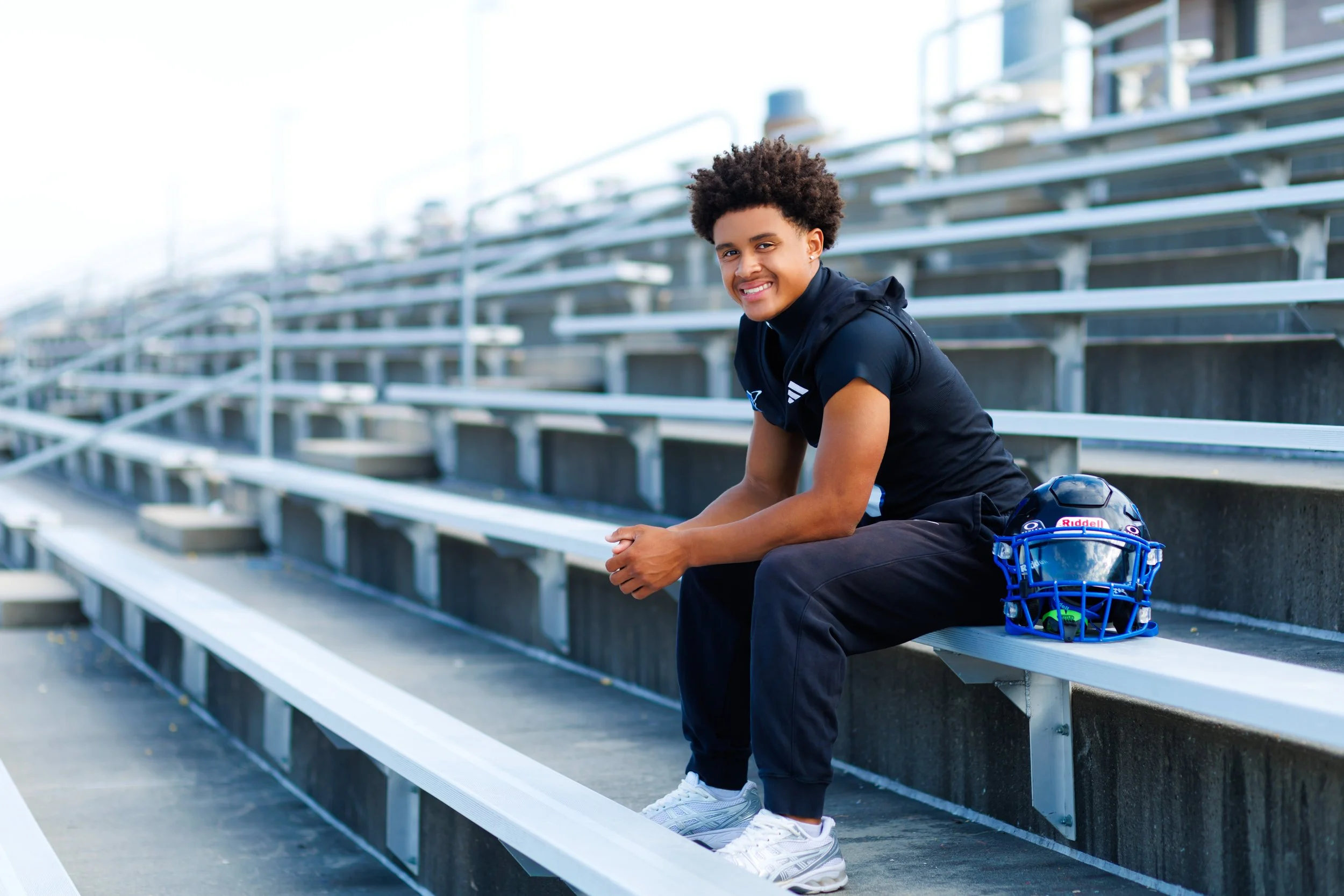 senior photo of boy in football gear on the bleachers