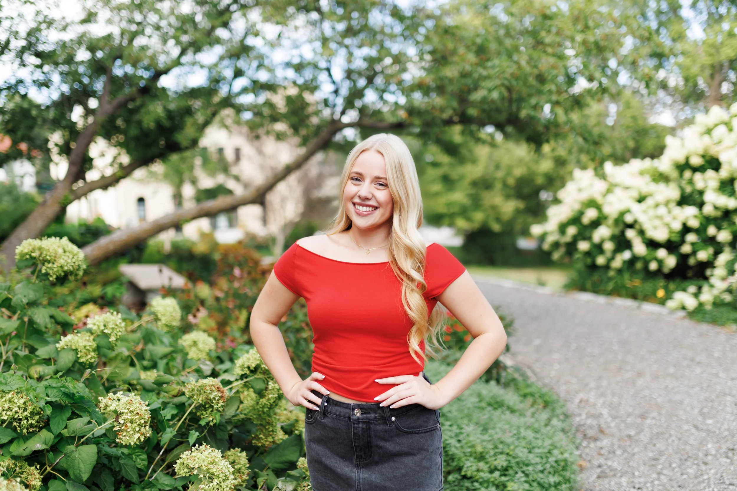 senior photo of a girl in a red shirt in a garden in Omaha, NE