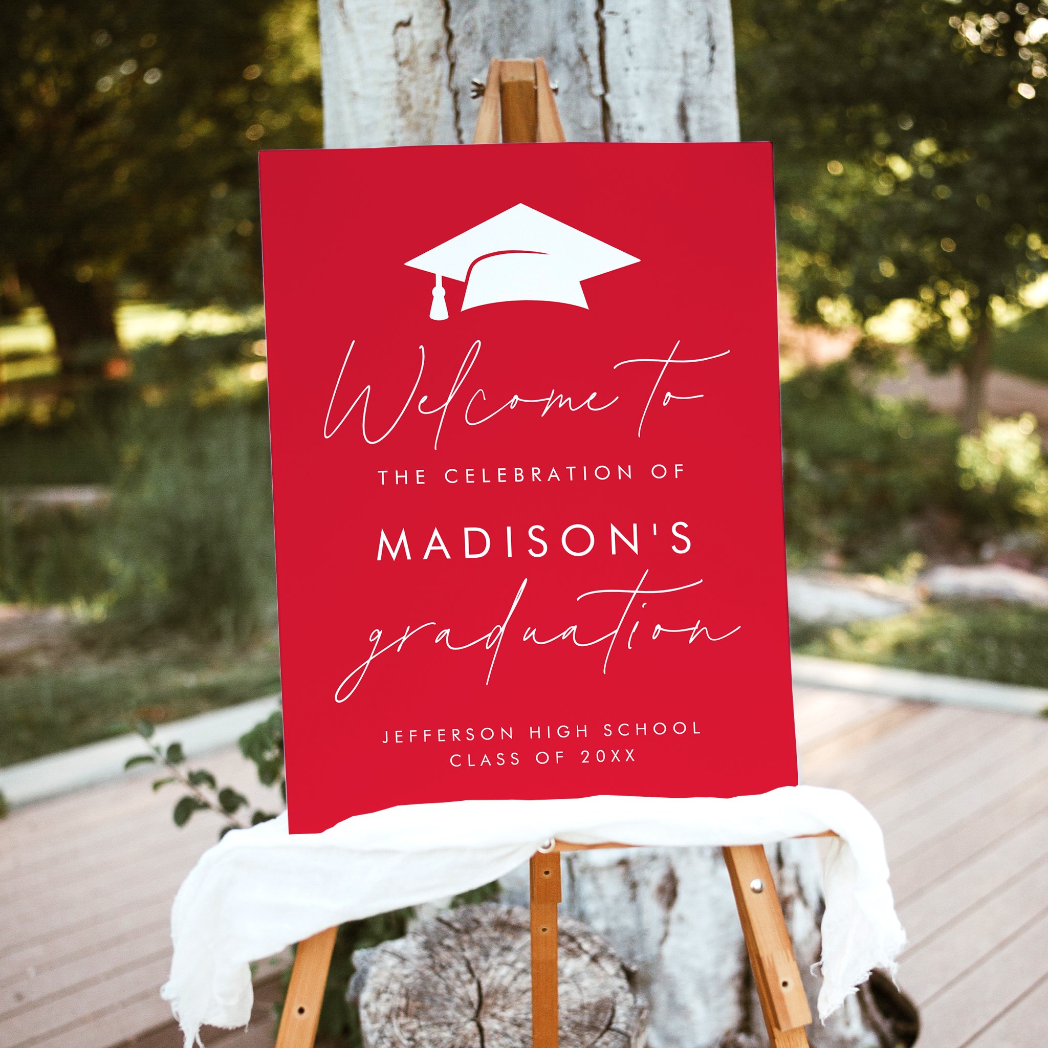 Red modern graduation welcome sign with white lettering, graduation cap illustration, and handwritten script accents