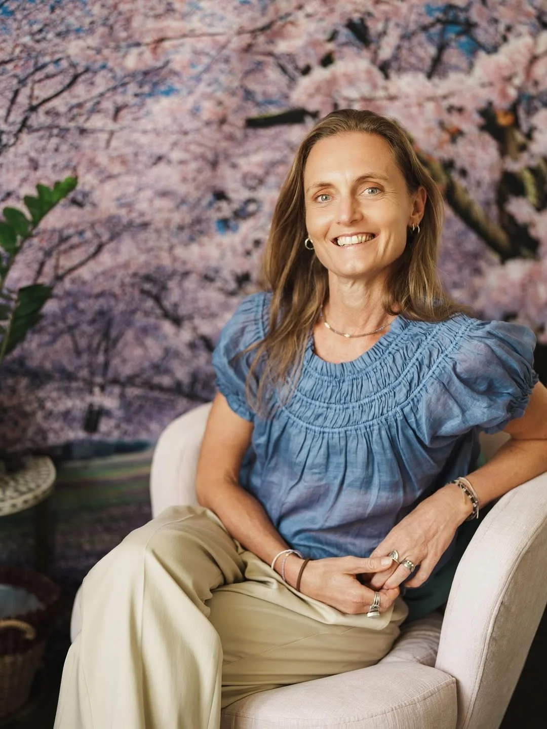 Kylie Rook, Hakomi Somatic Practitioner, sitting on a chair, smiling.