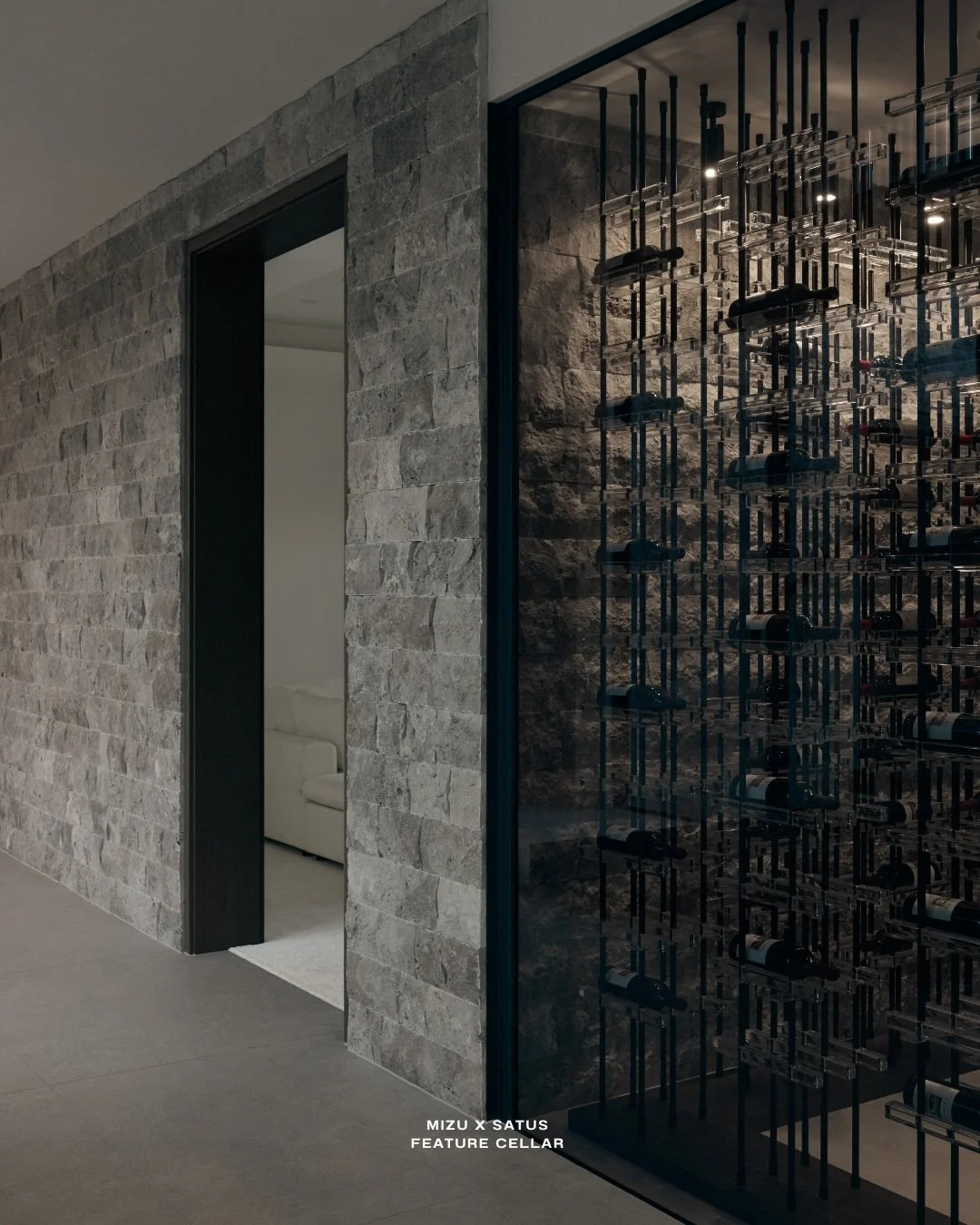 A space designed to be experienced, not just stored.

The feature cellar holds over 500 bottles, framed behind smoked glass to create a sense of depth and subtle reveal. Split-face silver travertine wraps seamlessly from the exterior wall into the ce