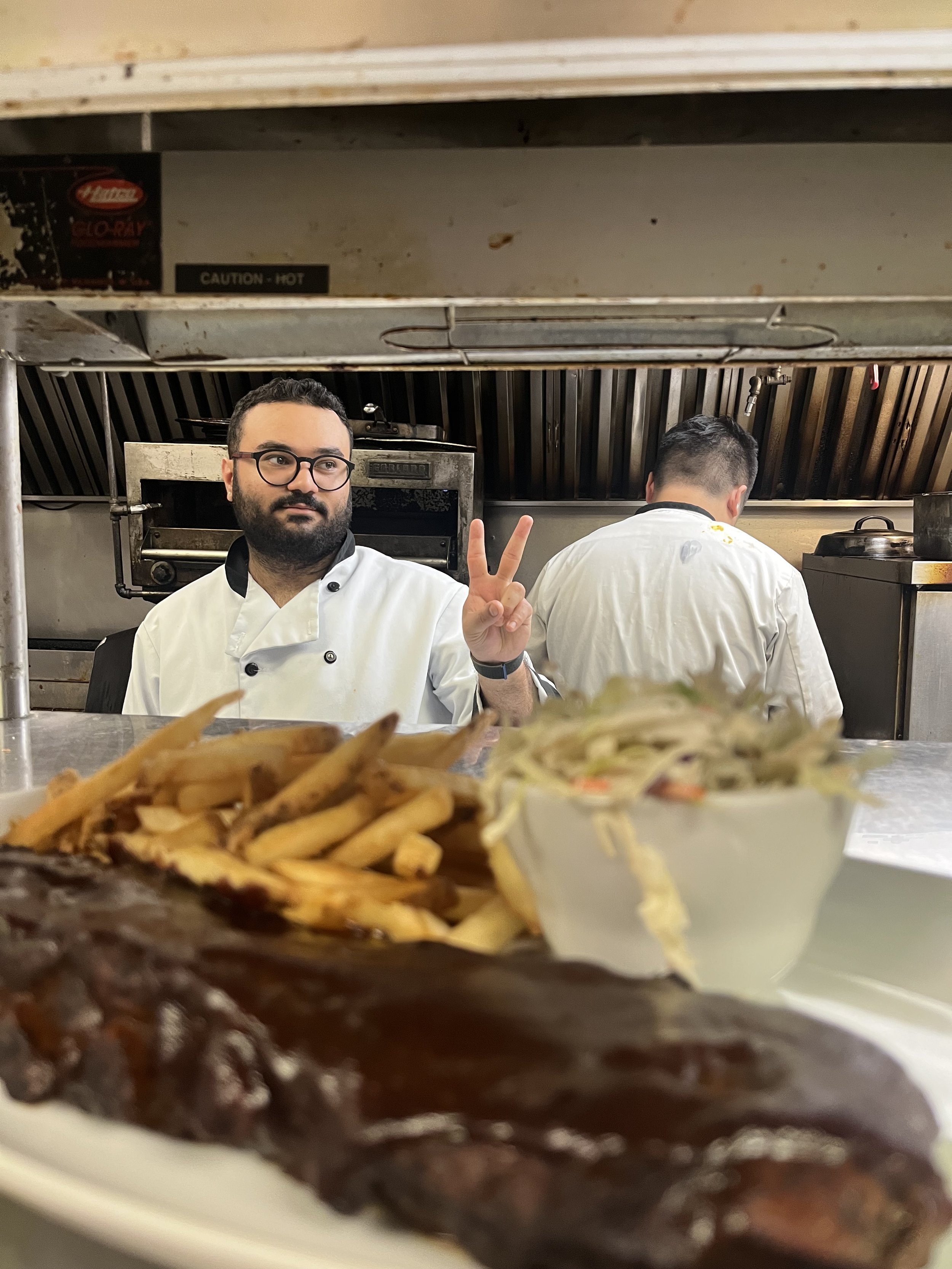 Chef with BBQ ribs, coleslaw, and side fries.
