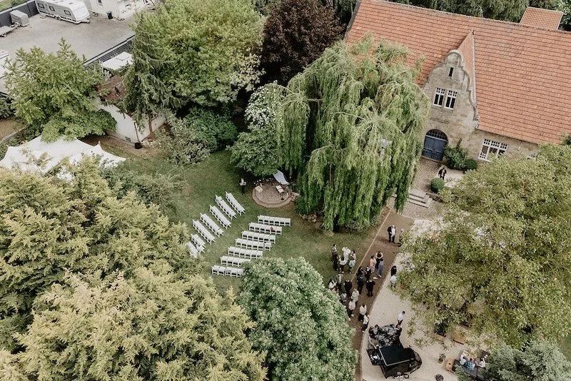 Luftaufnahme einer Hochzeitszeremonie im Garten unter einer Trauerweide