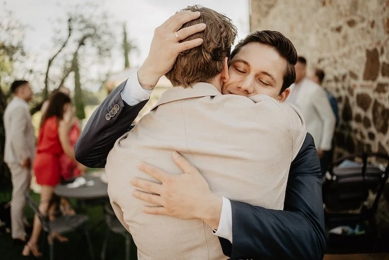Emotional hug between the groom and a guest during cocktail hour at a destination wedding in Tuscany.