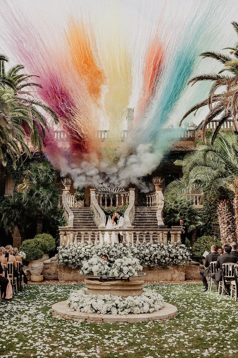 The bride and groom at their outdoor wedding ceremony at Castello Monaci in Puglia , with colored smoke and white floral decorations