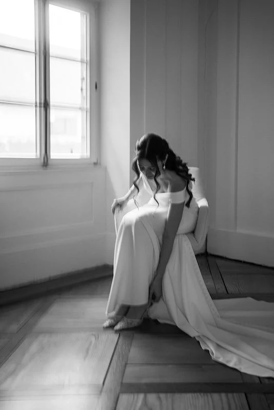 Ruhiger Moment der Braut am Fenster – natürliche schwarzweiße Hochzeitsfotografie