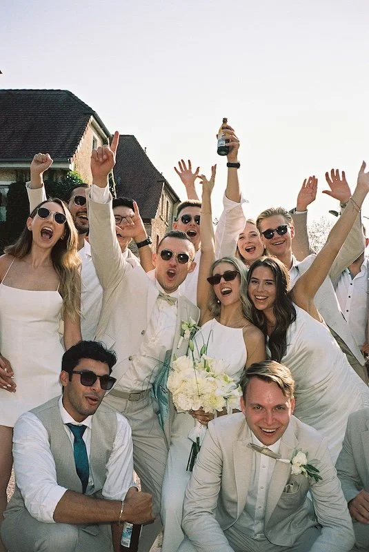 Ausgelassene Gruppe von Gästen jubelt und lacht in die Kamera während der Hochzeit im Hofgut Nonnenau