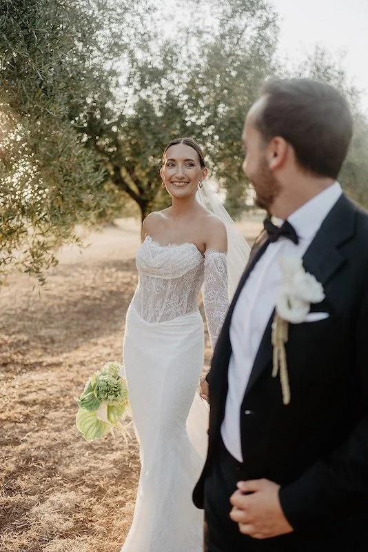 The bride walks toward the groom with a smile in the olive grove at Villa Boscarello in Tuscany