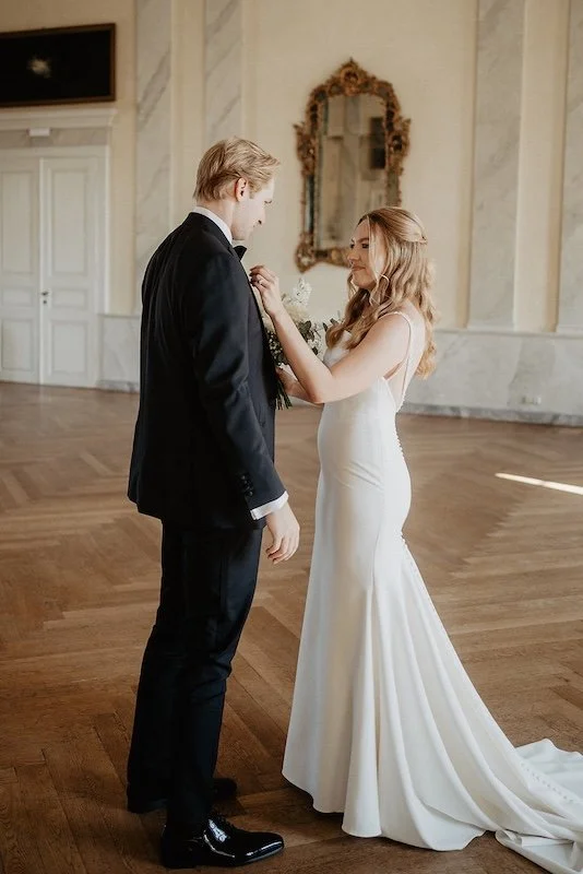 Braut steckt Bräutigam die Ansteckblume an bei eleganter Hochzeit im Schloss Johannisberg