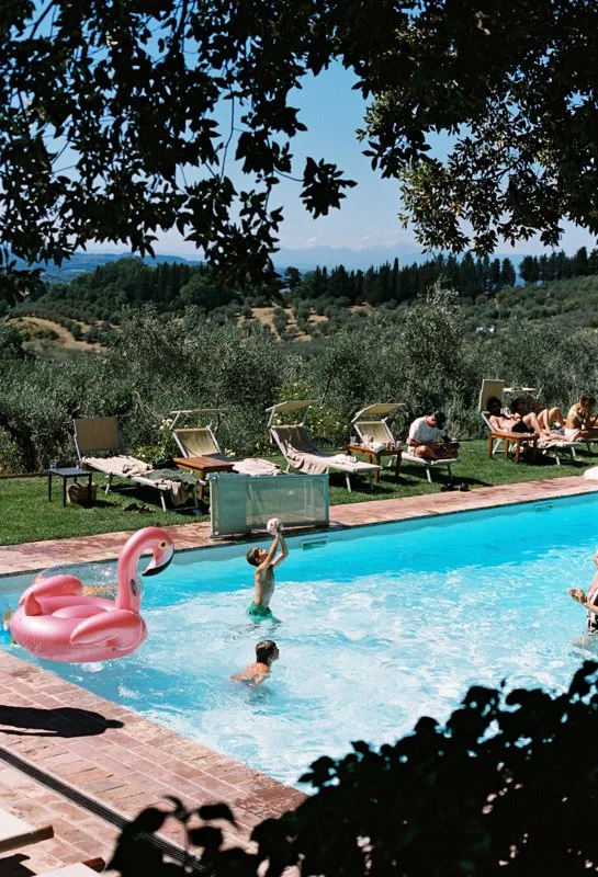 Wedding guests by the pool at Villa Il Poggiale, overlooking the olive groves of Chianti