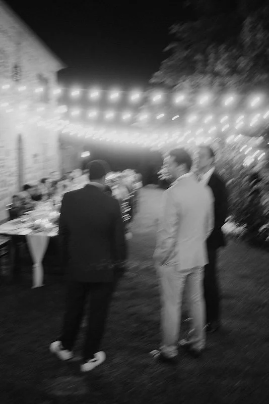 Evening view of an outdoor wedding reception at a Tuscan villa surrounded by rolling hills.