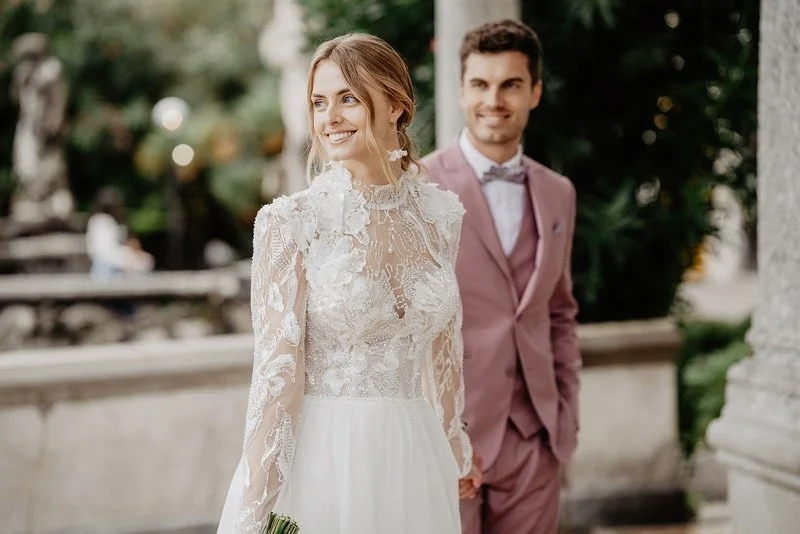 Braut im detailreichen Spitzenkleid und Bräutigam im modischen Pastellanzug - Hochzeitsfotografie mit italienischem Charme am Gardasee.