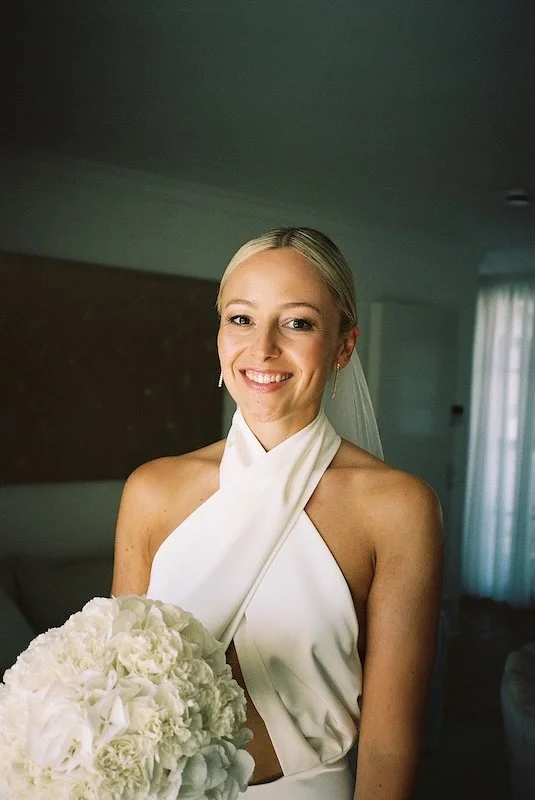 Analoges Porträt der Braut mit Blumenstrauß im warmen Licht, gekleidet in ein Kleid mit Halter-Ausschnitt