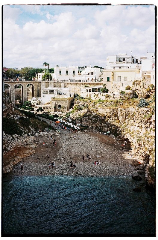 Analoge Aufnahme auf einem Portra 400 35mm Film mit Blick auf die Steilküste und den Strand einer apulischen Küstenstadt