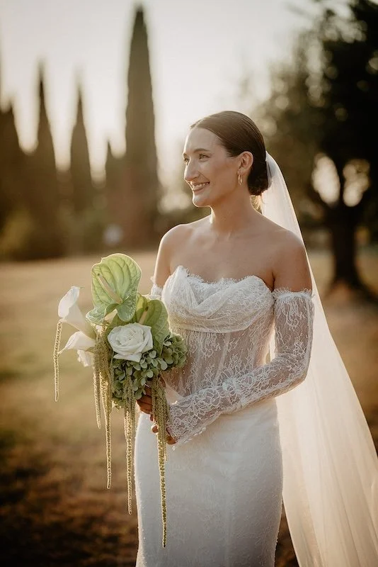 Bride with her bouquet and cypress trees in the background at the wedding at Villa Boscarello