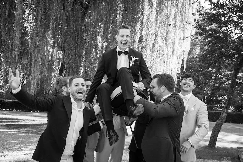 Freunde heben den Bräutigam während der Hochzeitsfeie