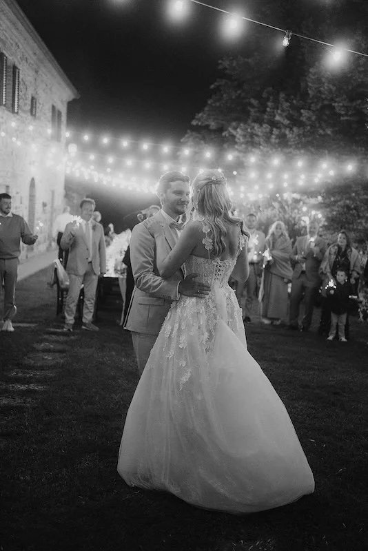 Brautpaar beim ersten Tanz unter Lichterketten bei einer Hochzeit in der Toskana