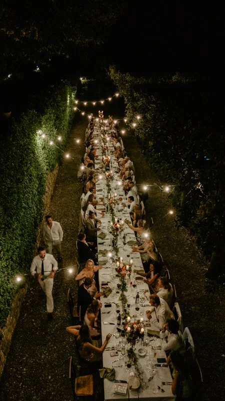 The bride and groom toast each other in the evening with raised champagne glasses, photographed from behind