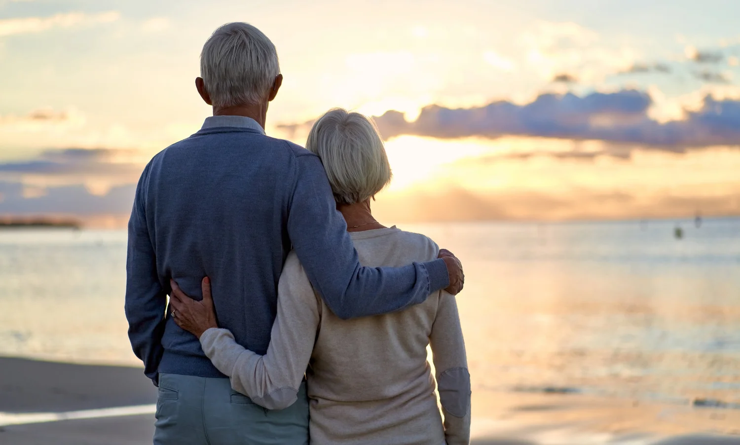 An older couple watching the sunset over the water