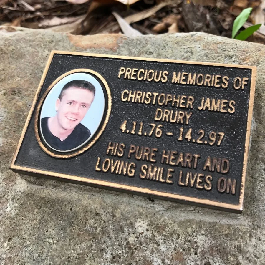 Bronze memorial plaque for Christopher James Drury, 4.11.76 to 14.2.97, reading: His pure heart and loving smile lives on