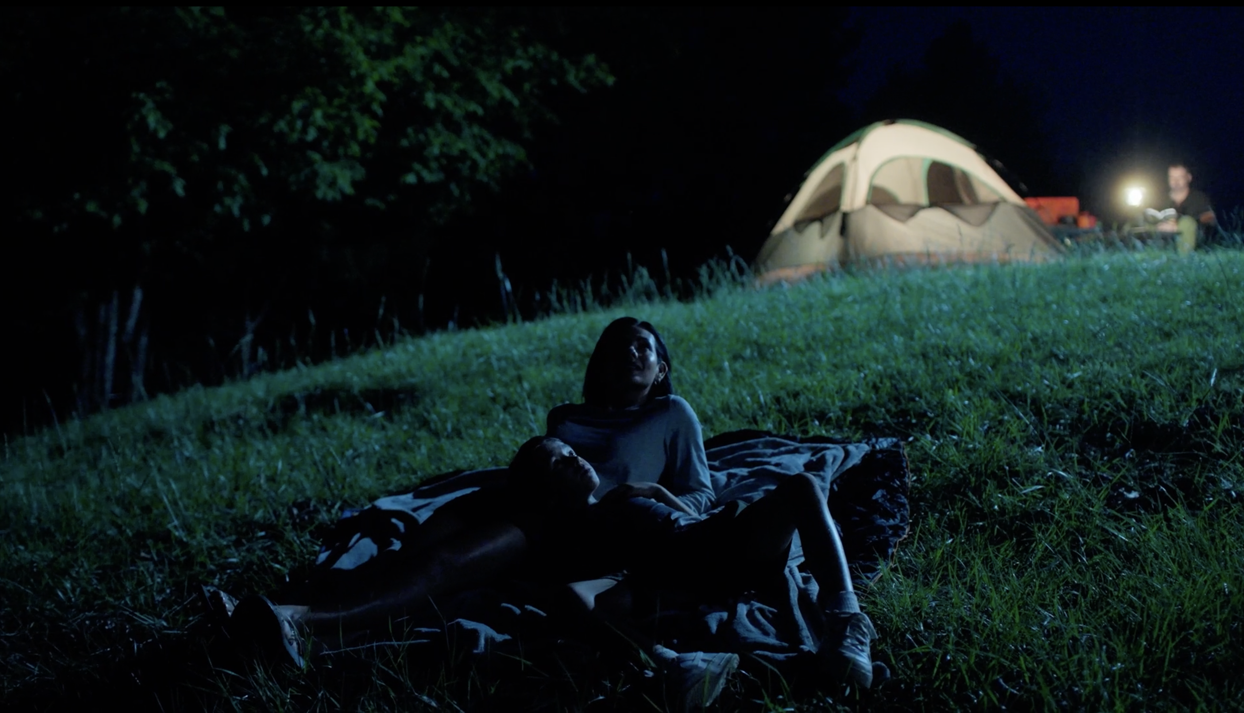 A mother and child laying on a blanket gazing at the night sky