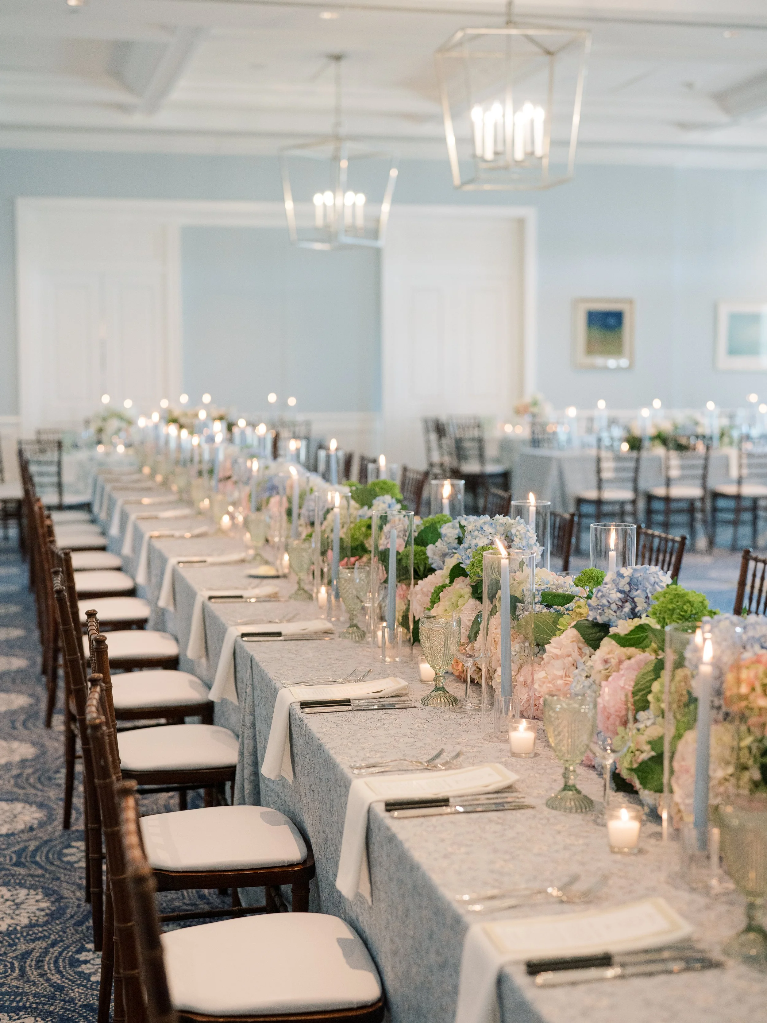 Elegant banquet table decorated with flowers and candles in a well-lit dining room.