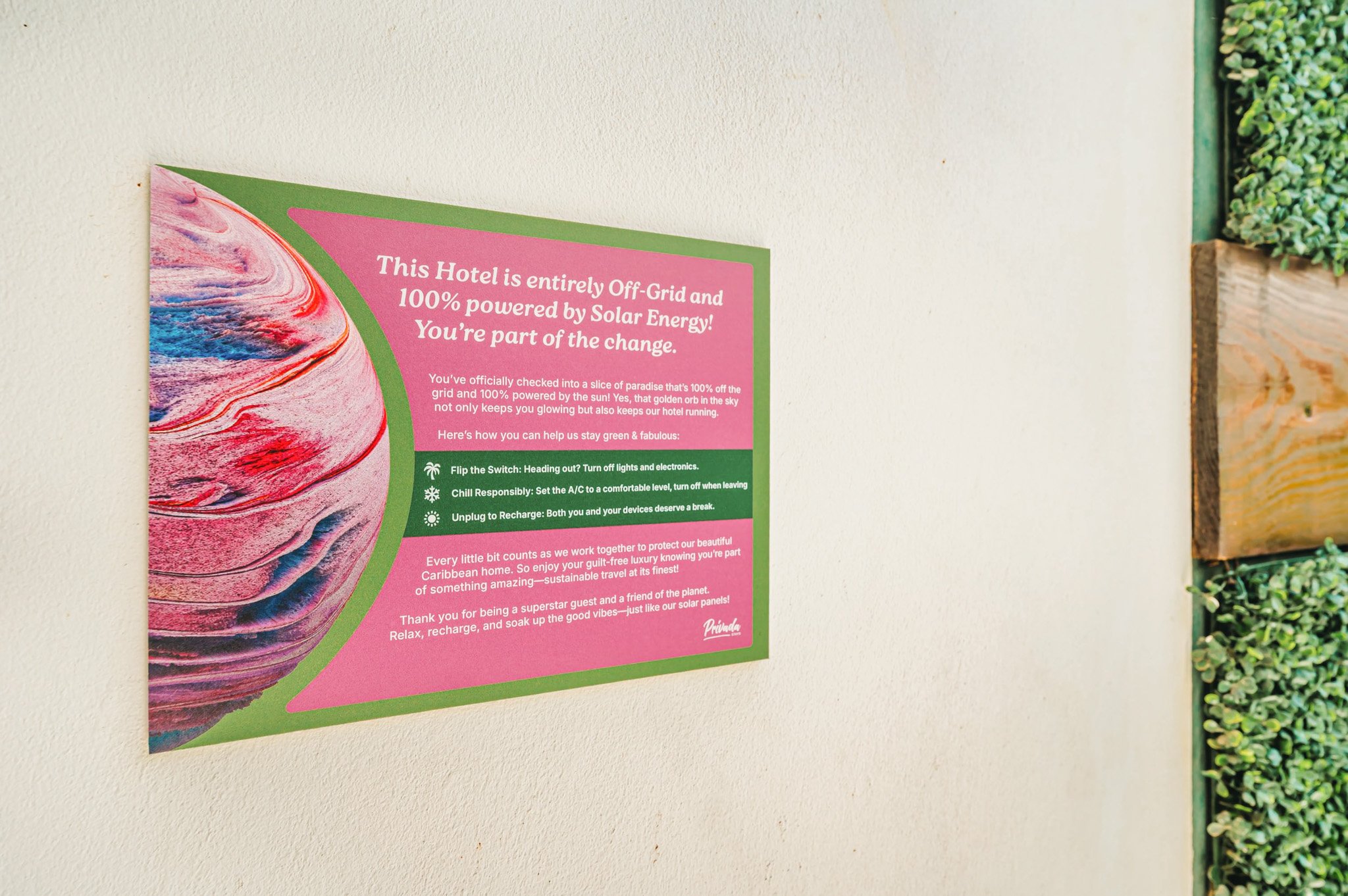 Hotel sign explaining the hotel is off-grid and powered by solar energy, with tips for guests on sustainability, and decorative greenery to the side.