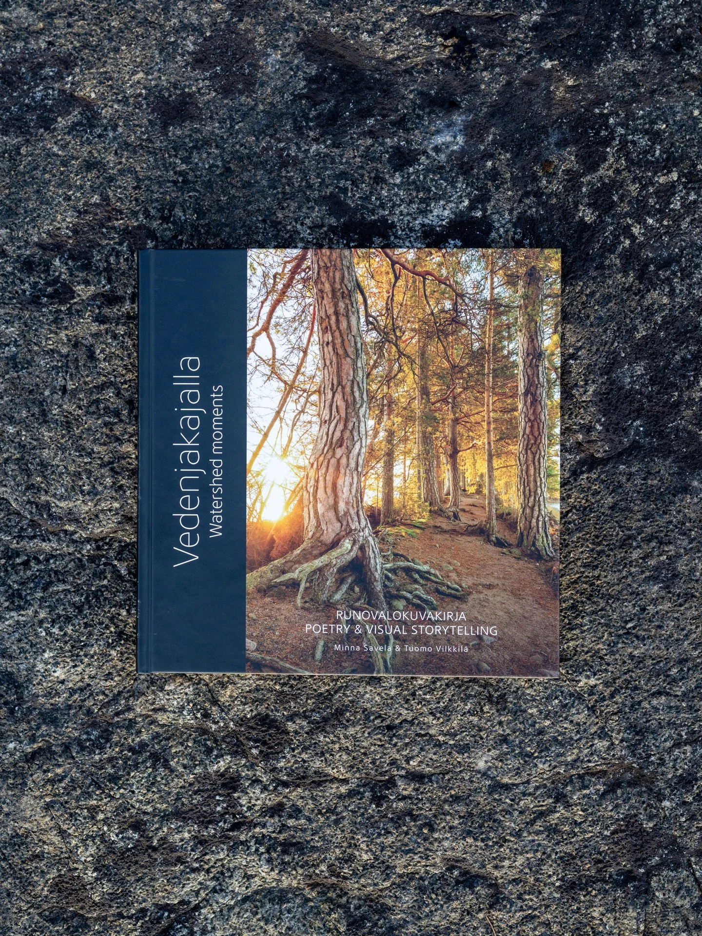Vedenjakajalla-runovalokuvakirja kalliolla