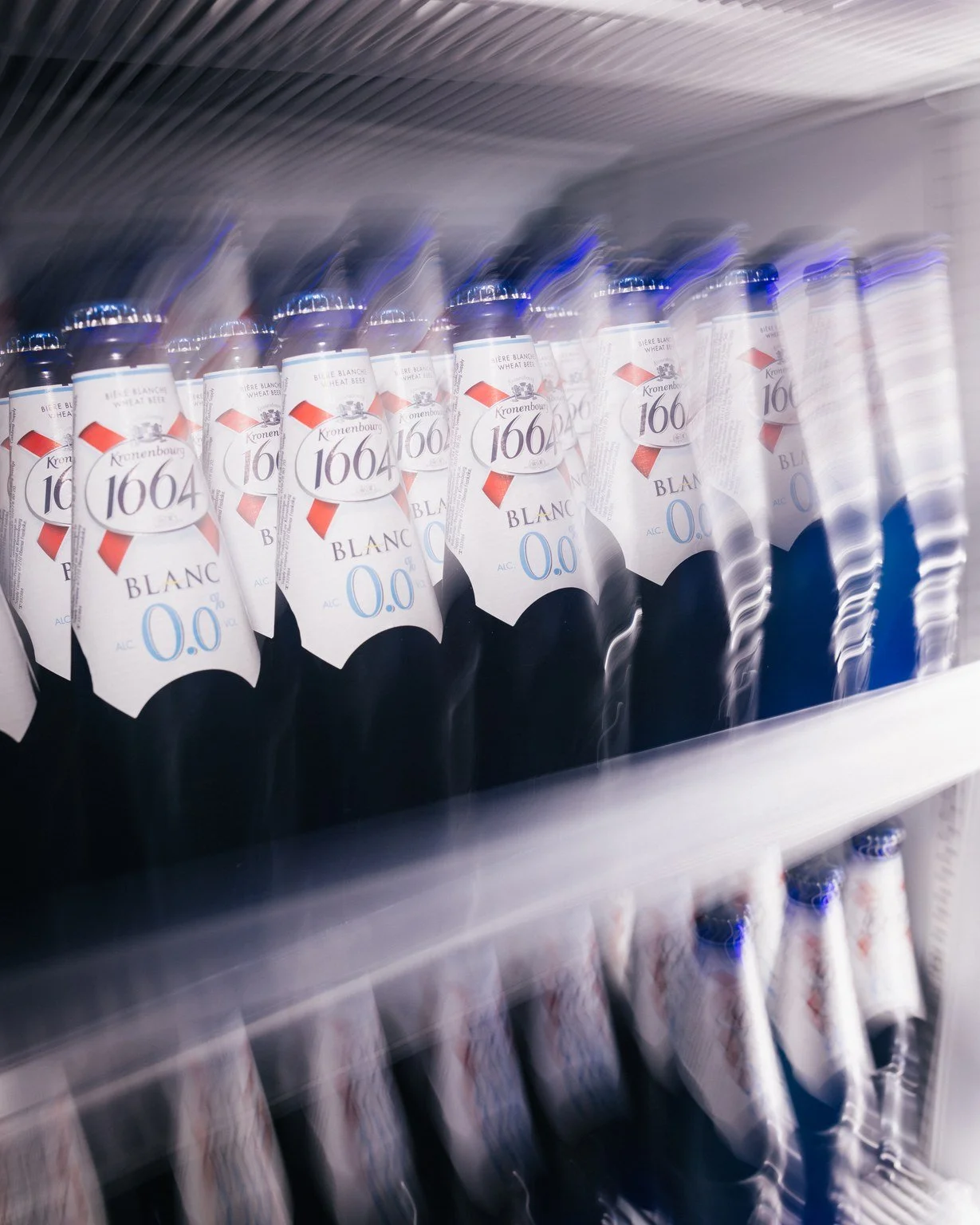 Row of beer bottles inside a refrigerator with a blurred motion effect.