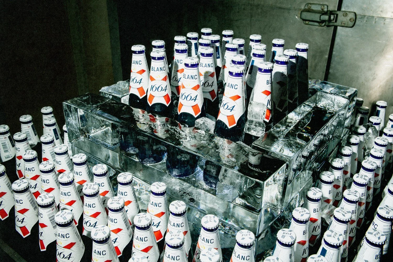Bottles of Bud Light beer in an ice-filled container with ice cubes on top.