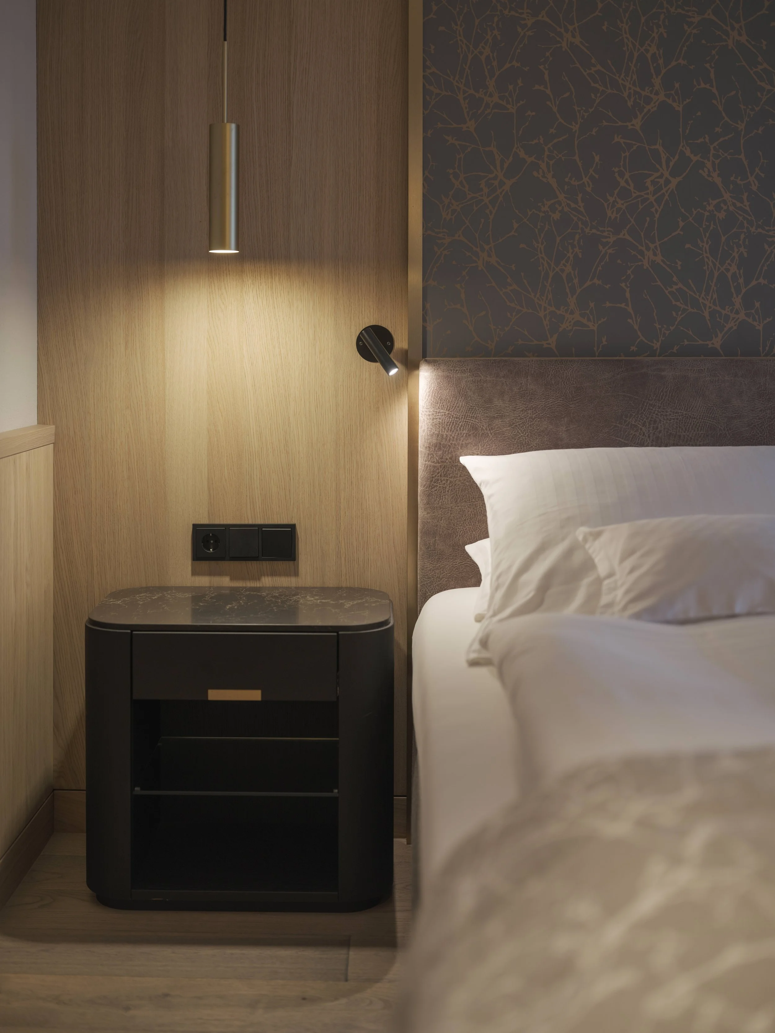 Nahaufnahme eines modernen Schlafzimmers, Bettrahmen mit weißer Bettdecke, Nachttisch und Wandleuchte