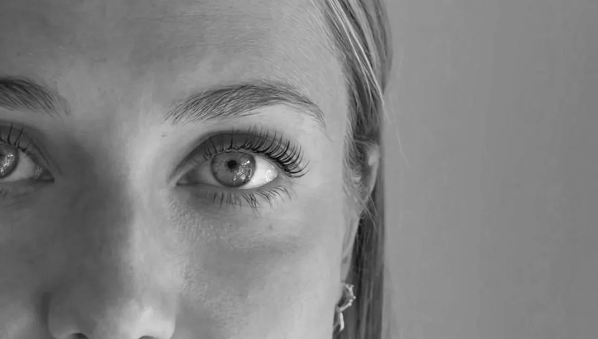 Close-up of a woman's face showing her eye and eyebrow in black and white.