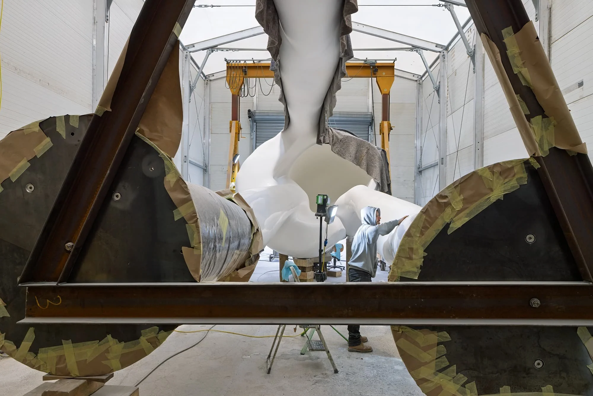 Blick durch die Basis in den Kopf der liegenden Großskulptur bei Schleifarbeiten.