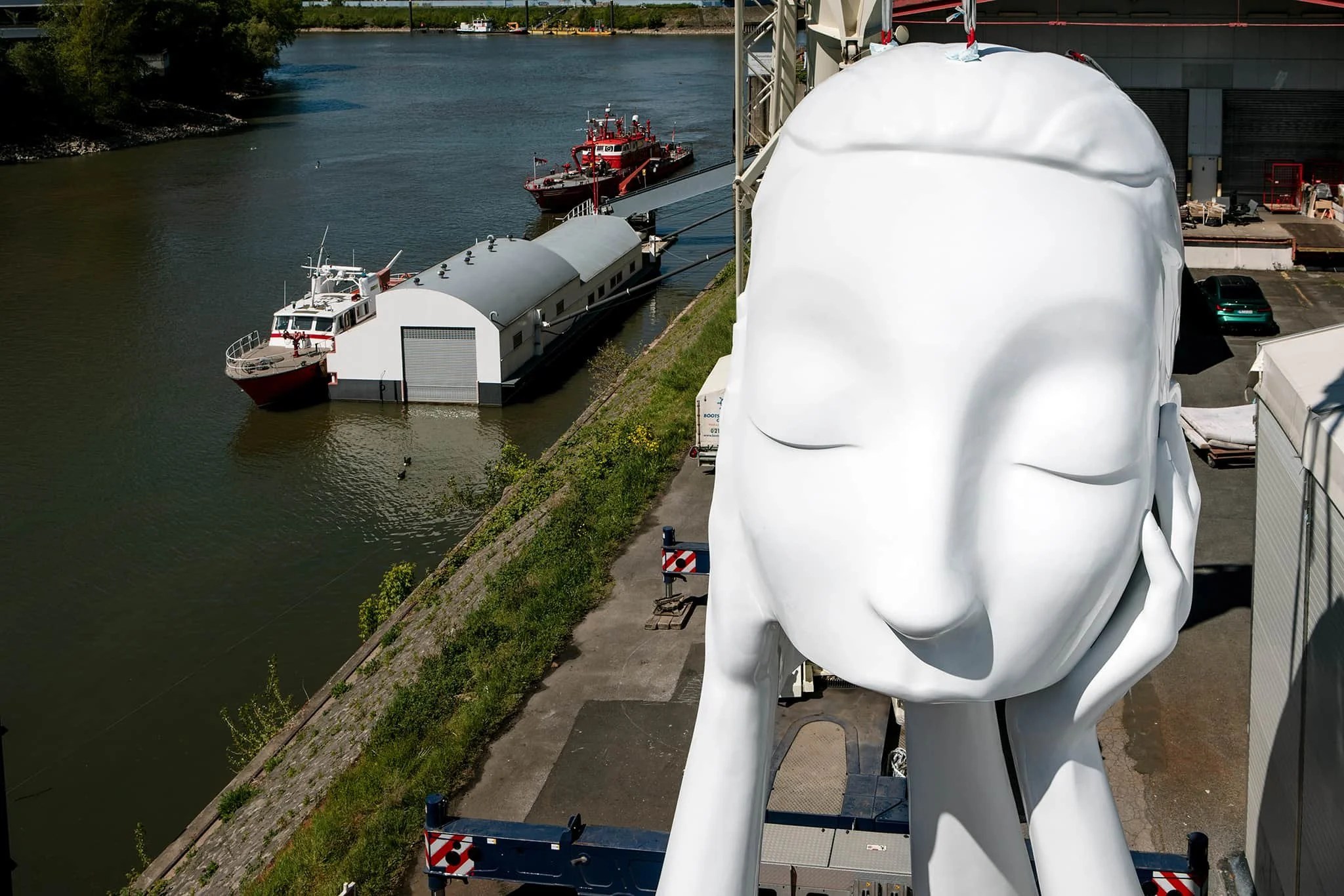 Blick von einem Scherenhubwagen auf den Kopf der Großskulptur von Andreas Schmitten. Im Hintergrund der Medienhafen Düsseldorf.