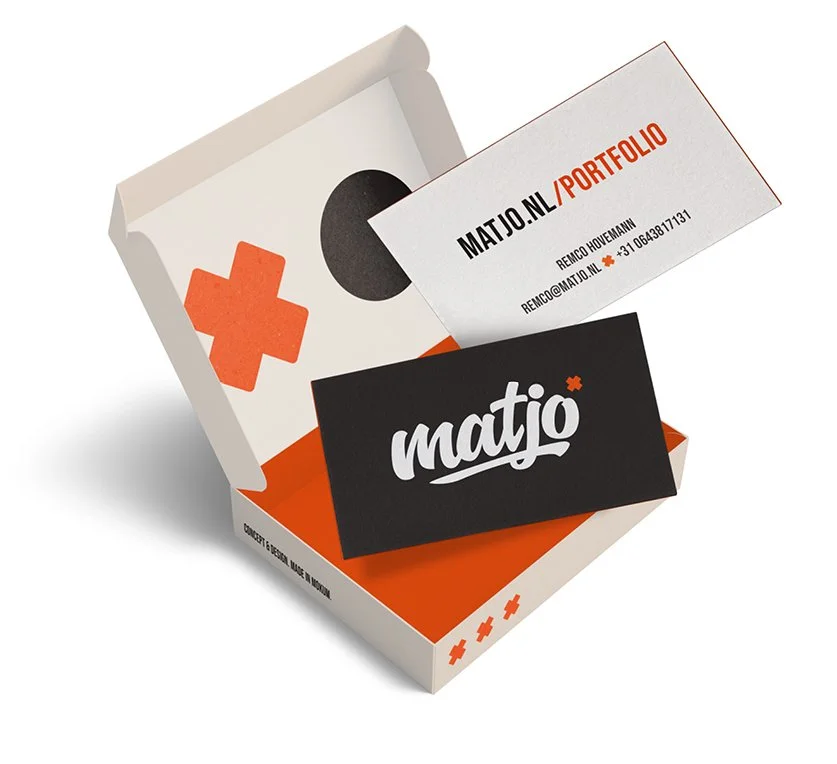 Een doos met een zwart en een wit kaartje, een visitekaartje en een zwart bord met het logo 'matjo'.