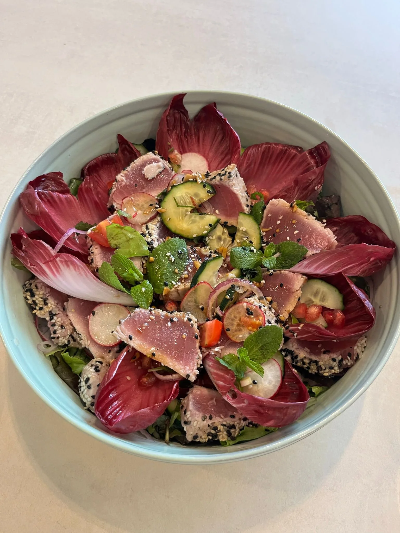 Sesame-Crusted Tuna Tataki Salad  Sesame-crusted tuna tataki served over mixed greens with radicchio, cucumber, radish, cherry tomatoes, fresh herbs, and citrus-soy vinaigrette.