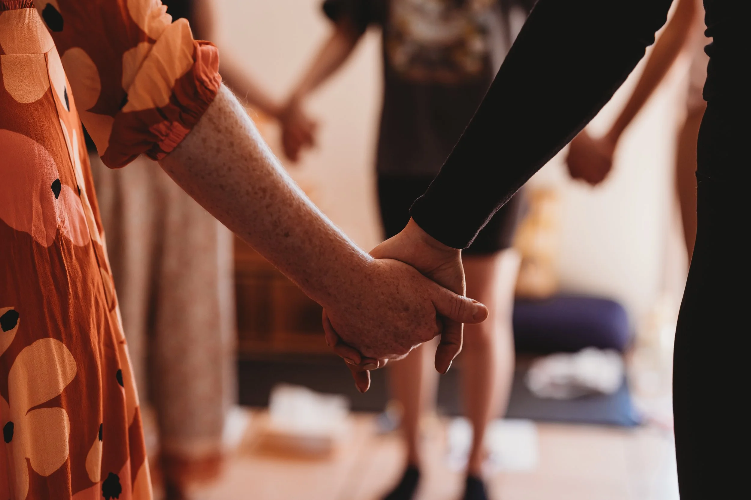 Close-up of multiple people holding hands in a circle during a social gathering or event.